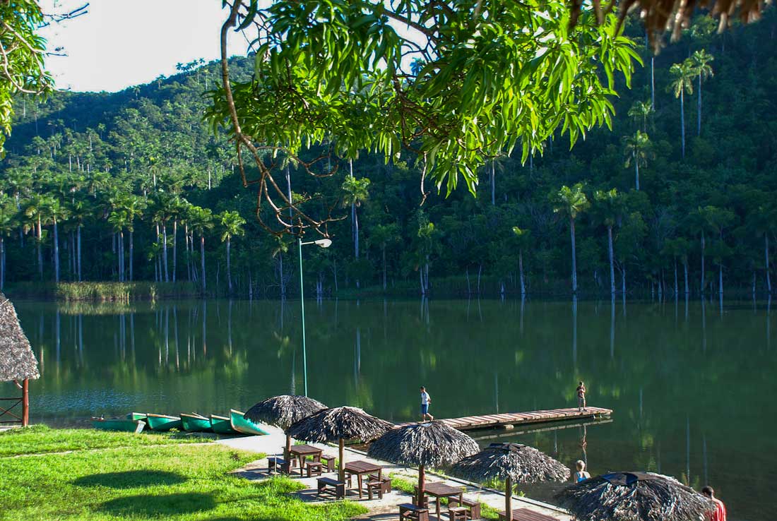 river bank with canoes, grass lawn and mountains