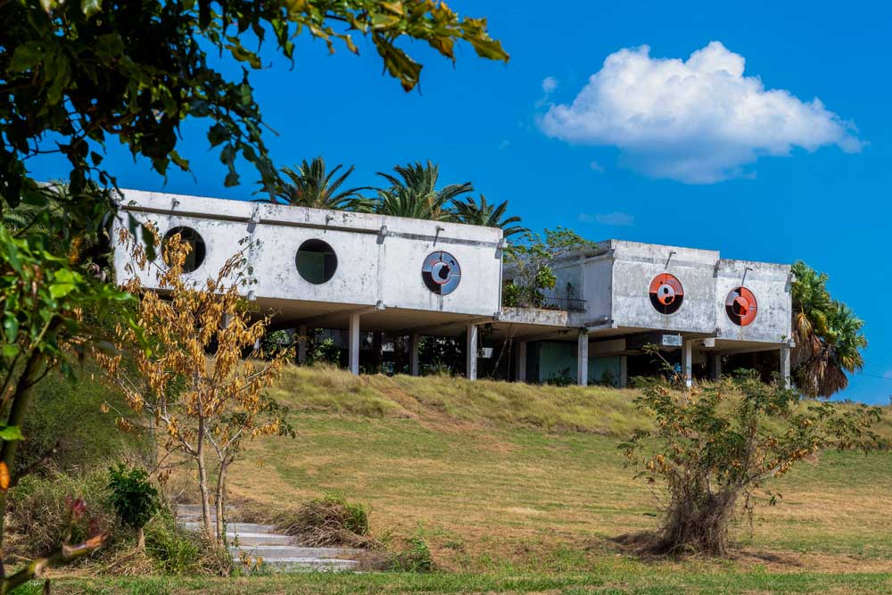 Abandoned concrete building on stilts with broken glass windows